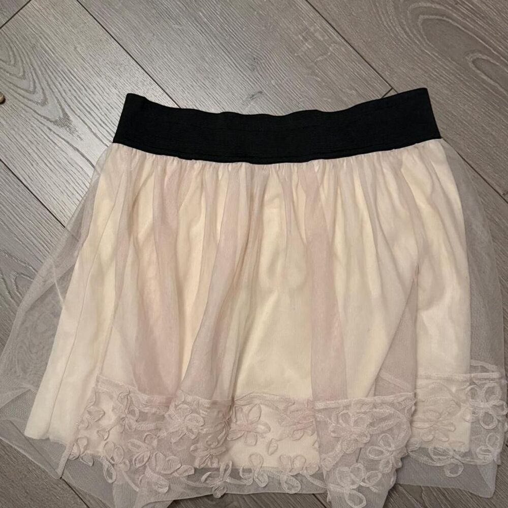 cream-colored tulle and lace mini skirt features a black elastic waistband